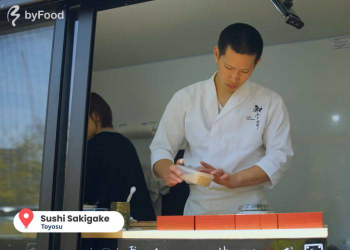 The chef at the Sushi Sakigake Food Truck preparing his famous bara chirashi in a white chef's coat.